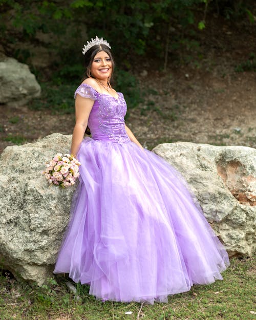Beautiful Young Woman in Purple Dress Posing on Rocks