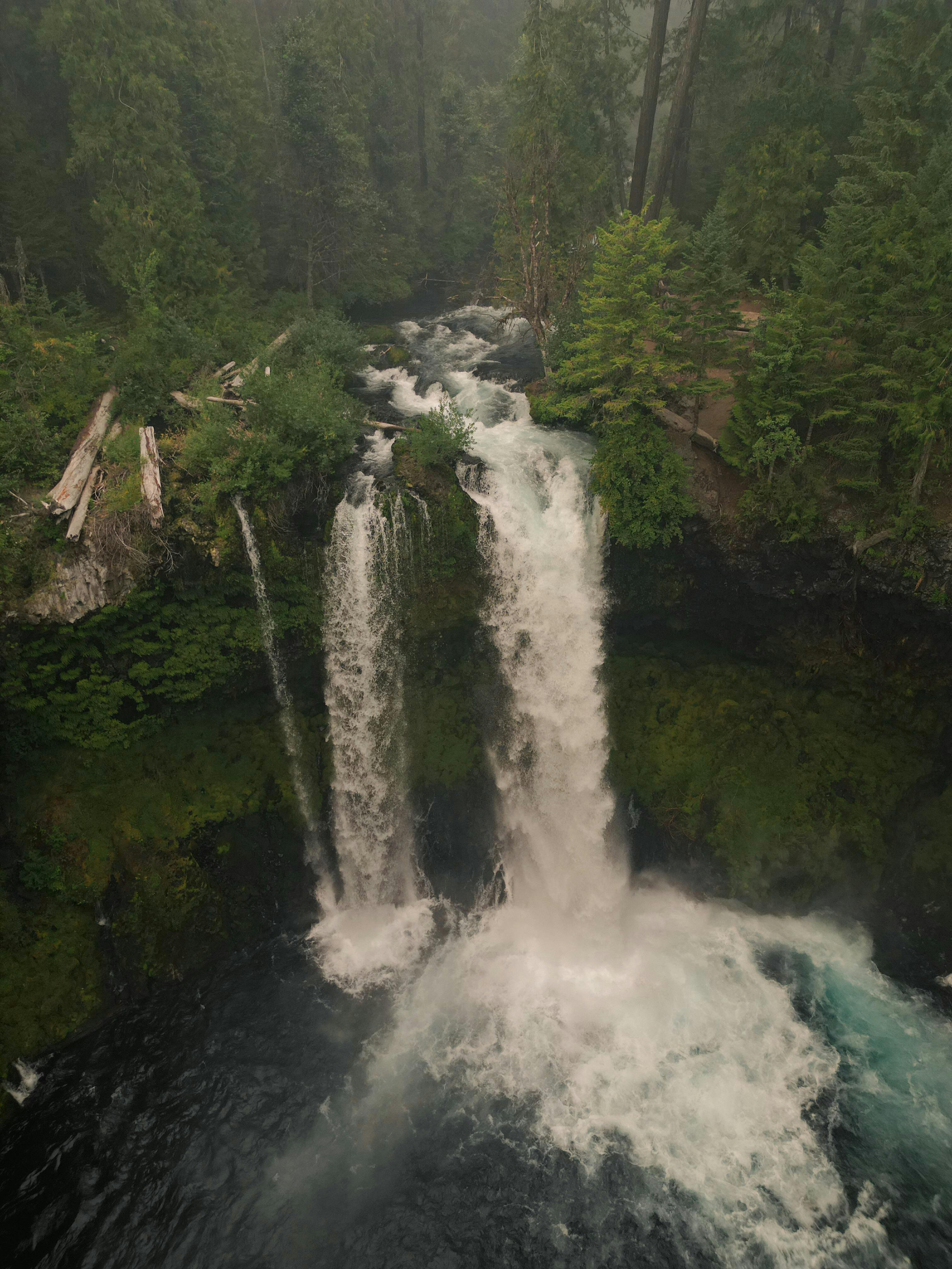 A stunning aerial view of a waterfall cascading through lush forests in Oregon, United States.