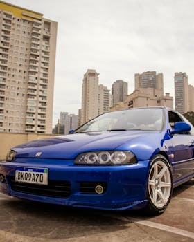 A sleek blue Honda Civic parked against a bustling city backdrop with towering buildings.
