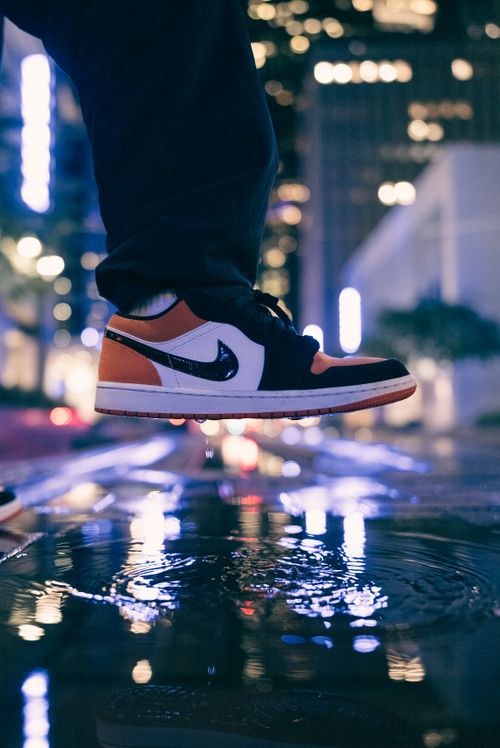 Free Close-up of sneakers reflecting city lights in a rainy urban night setting. Stock Photo