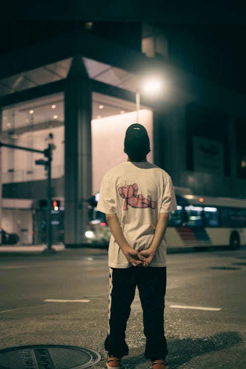 Man in T-shirt Standing on Street at Night