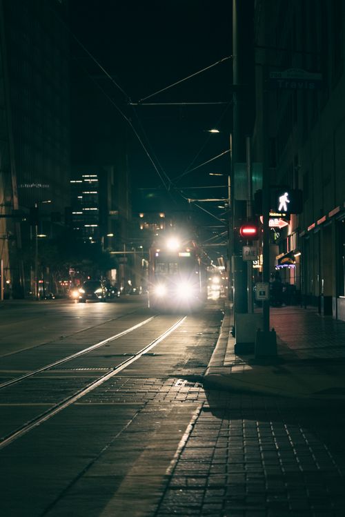 Free Moody city street at night featuring a tram and urban lights. Ideal for urban exploration themes. Stock Photo