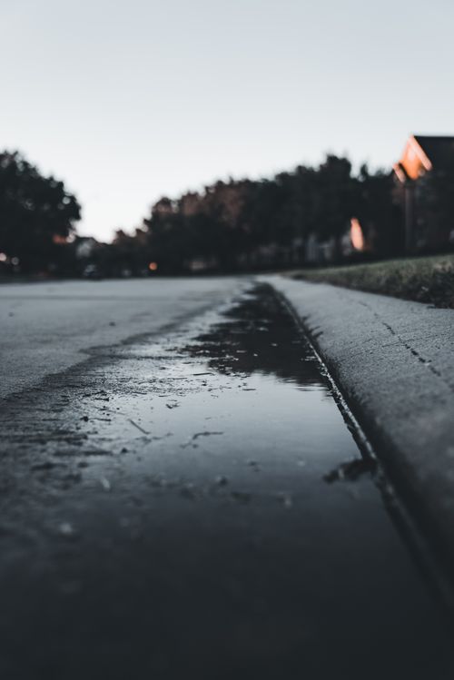 Free Puddle reflecting cityscape at twilight, capturing a moody urban scene with subtle lighting. Stock Photo