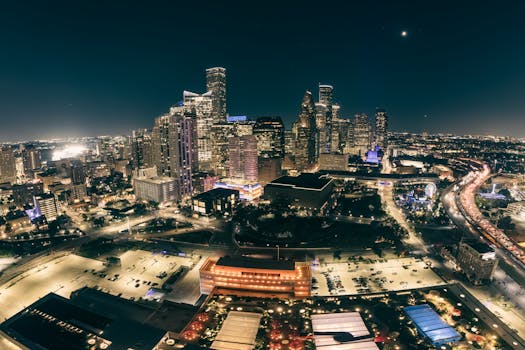 A stunning aerial view of a city skyline illuminated at night, showcasing modern skyscrapers and bustling streets.