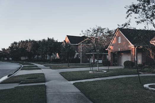 A serene suburban scene featuring brick houses and landscaped lawns at dusk.