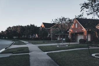Brick houses and landscaped lawns at dusk — photo by Erik Mclean on Pexels