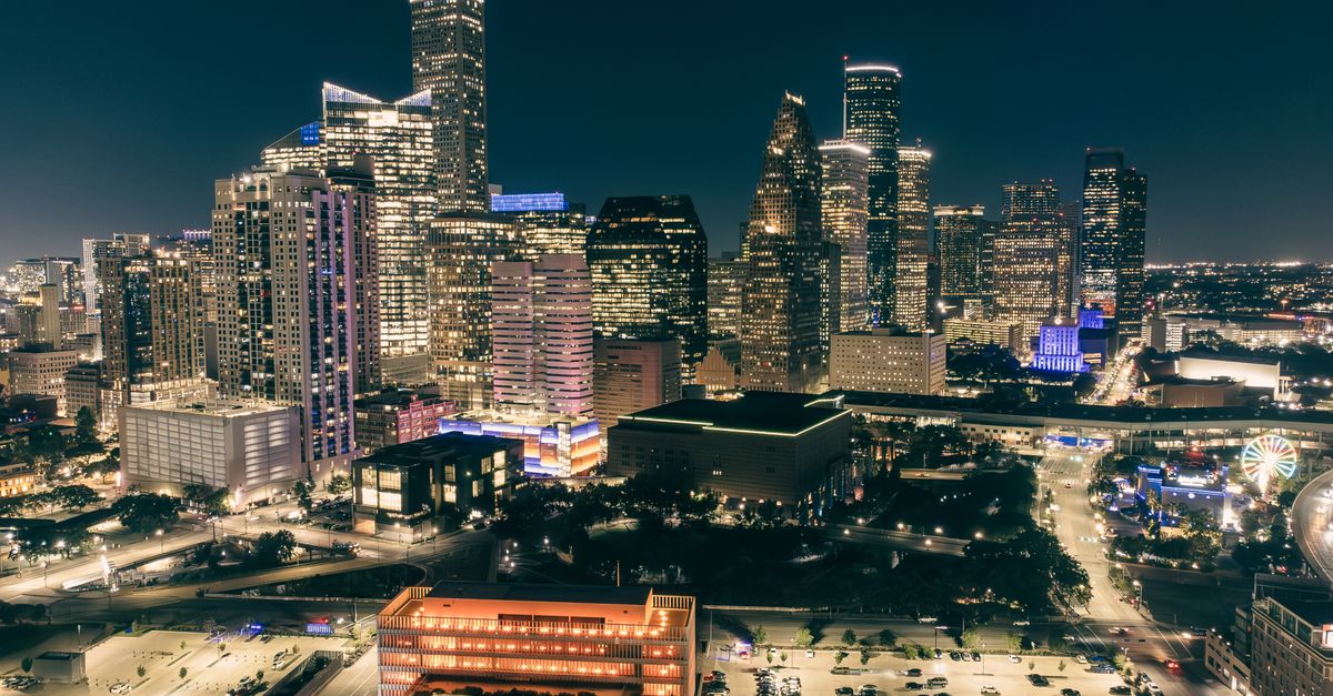 Stunning aerial view of a city skyline illuminated at night, showcasing modern architecture.