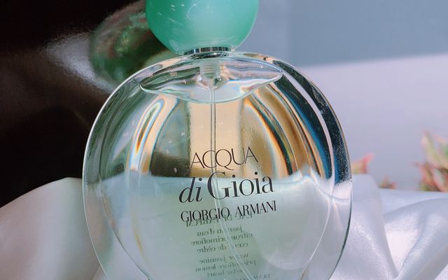An Acqua di Gioia perfume bottle on white fabric
