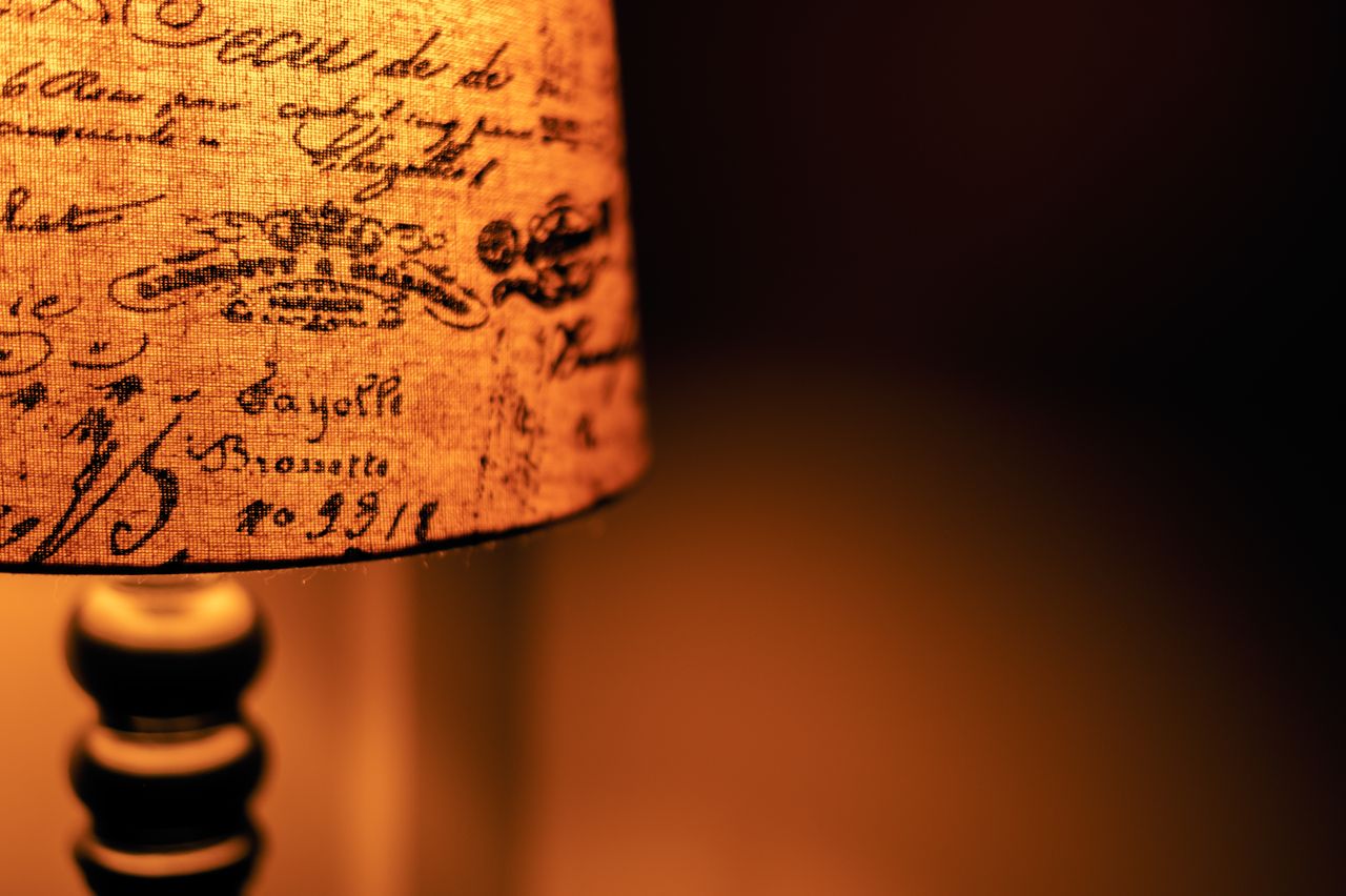 close up of a vintage lamp with a scripted fabric shade casting warm l