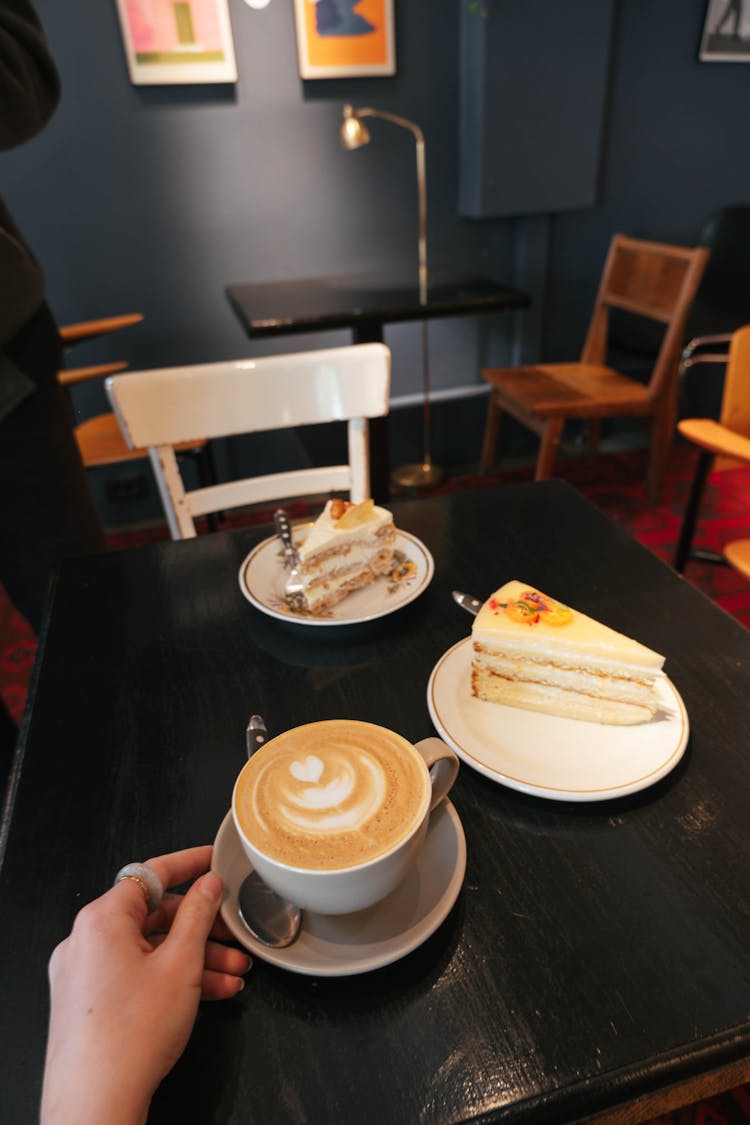 A Coffee And Slices Of Cake Standing On A Table In A Cafe