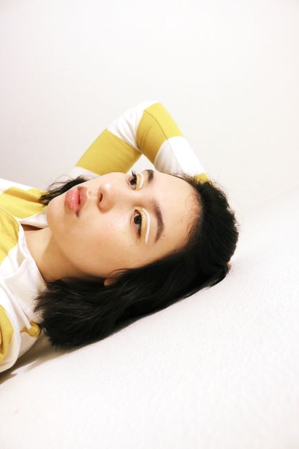 Close-up portrait of a brunette adult woman in yellow striped attire, indoors.