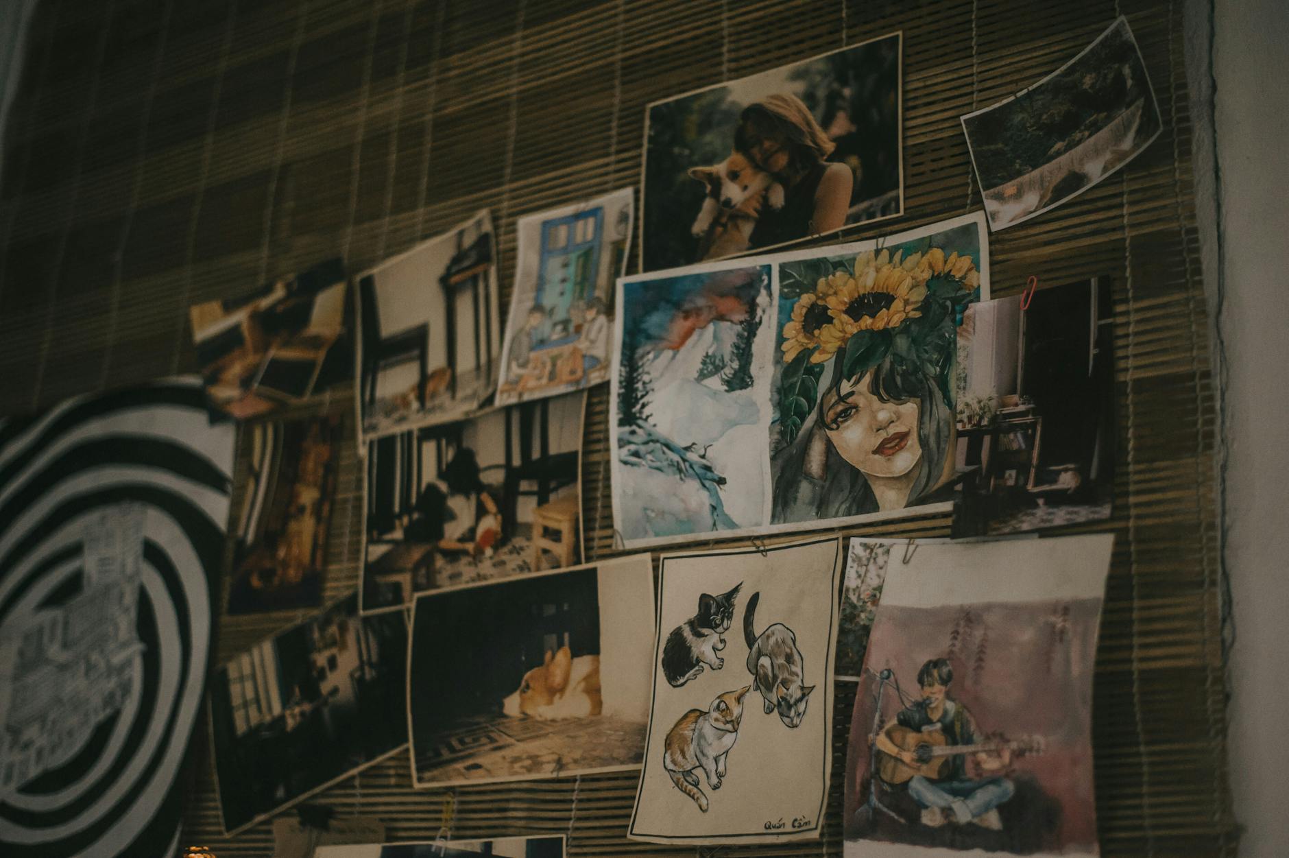 A creative collection of artworks and photographs displayed on a bamboo wall, showcasing vibrant colors and diverse styles.