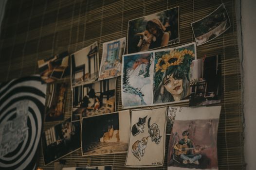 A creative collection of artworks and photographs displayed on a bamboo wall, showcasing vibrant colors and diverse styles.