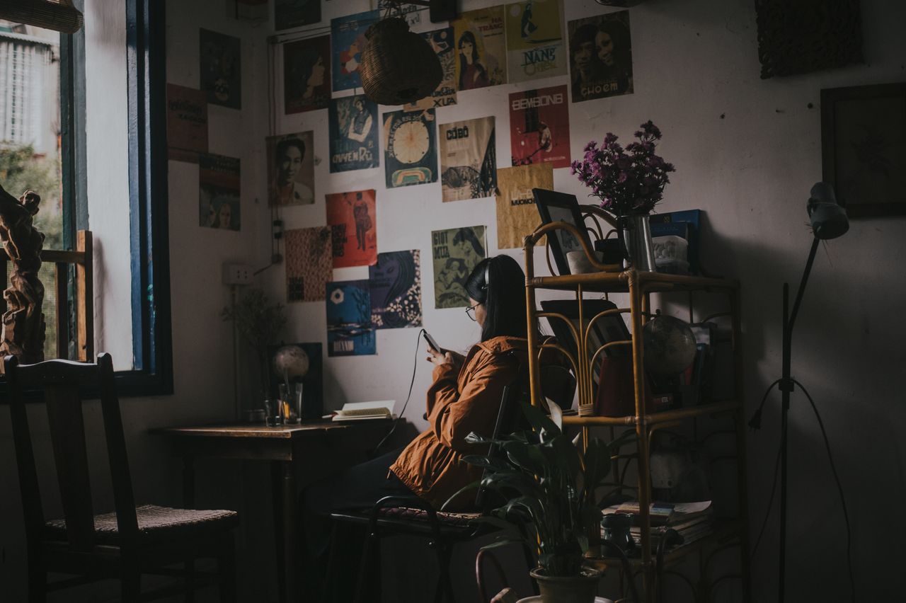 asian woman relaxing in a vintage living room using a cellphone surrou