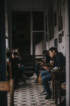 三个年轻人在室内弹吉他放松，营造出舒适的音乐氛围