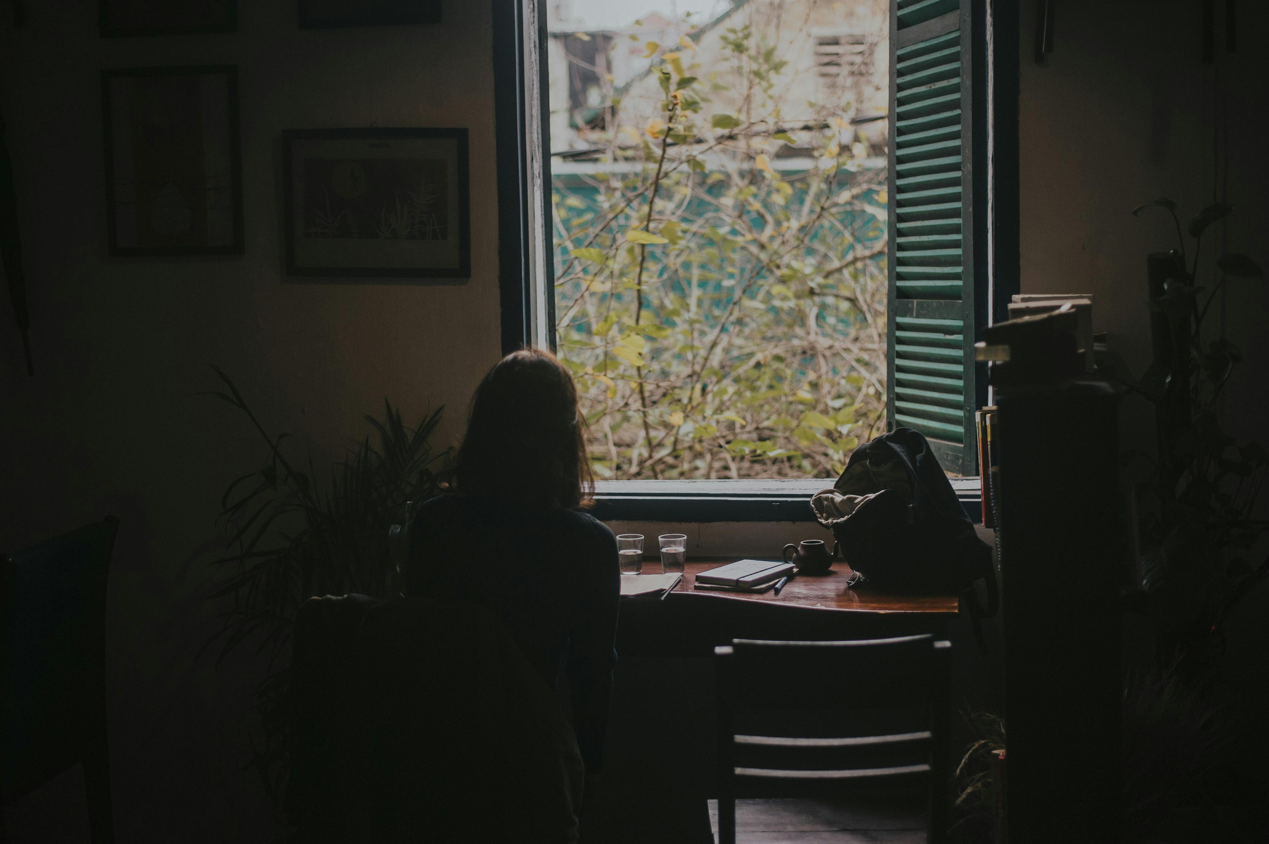 close up photography of woman sitting on chair watching view of outside