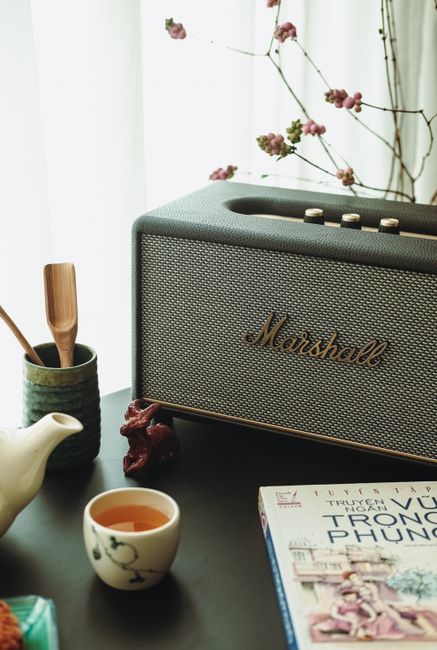 Cozy indoor scene with a Marshall speaker, tea set, and a book enhancing a relaxing atmosphere.