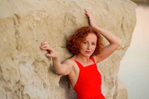 Redhead Woman in Red Dress against Rock
