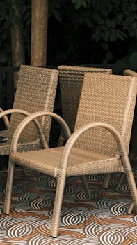 Stylish rattan chairs arranged on a unique patterned floor with a forest backdrop.
