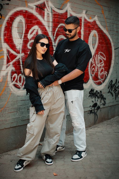 Couple in Sunglasses Standing by Wall