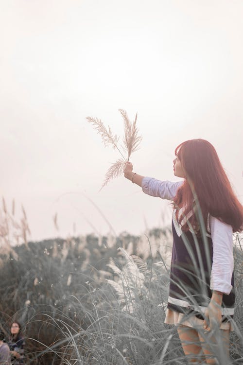 Woman Raising Right Arm With Grasses
