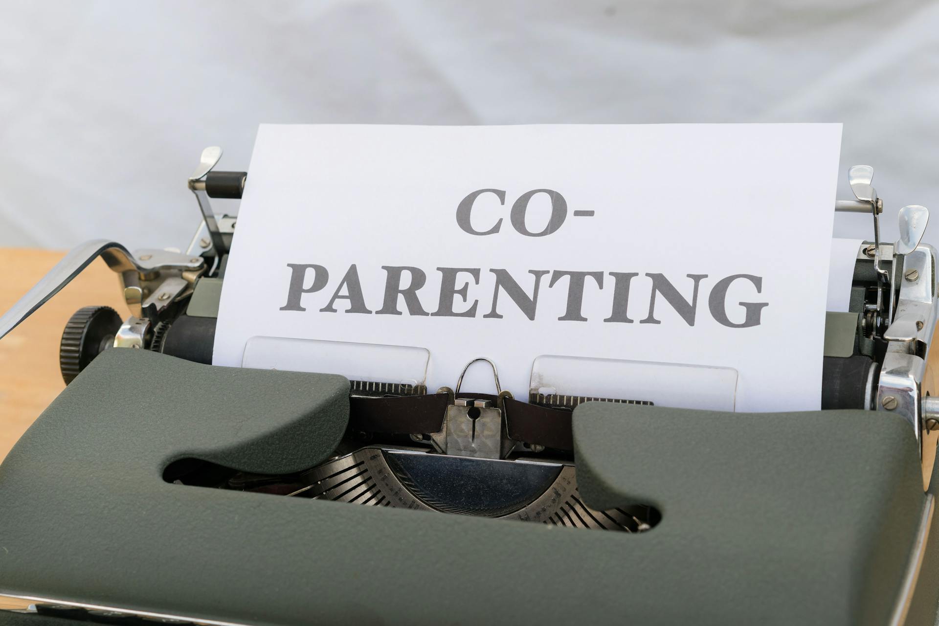 A vintage typewriter displaying a paper with the word 'Co-Parenting', symbolizing shared parenting or custody.