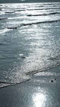 Close-up of sunlit waves gently lapping at the shore, creating a peaceful seaside vibe.
