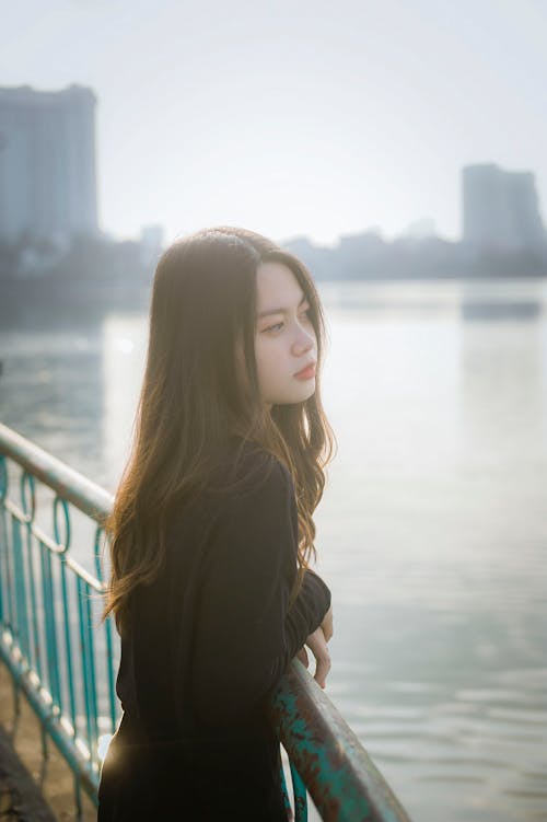 Woman Wearing Black Long-sleeved Shirt Leaning on Green Metal Railing