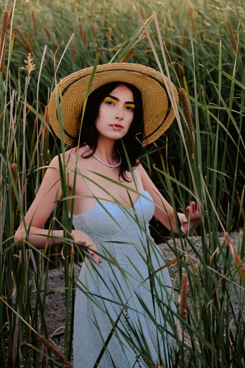Model With Rushes Face Model Woman Posing in Hat and Dress among Rushes · Free Stock Photo