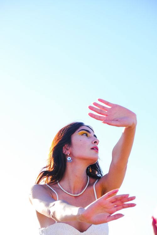Free Artistic portrait of a fashionable woman with arms outstretched, captured in natural light. Stock Photo