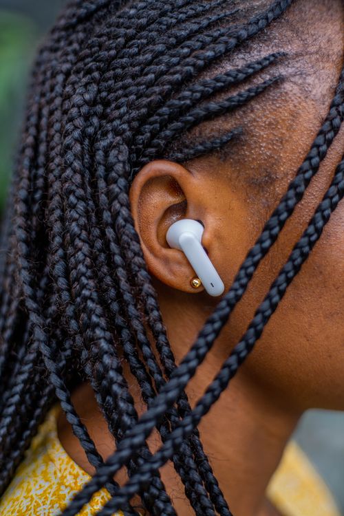 Free Close-up shot of a woman wearing earbuds and showcasing intricate braided hair. Stock Photo