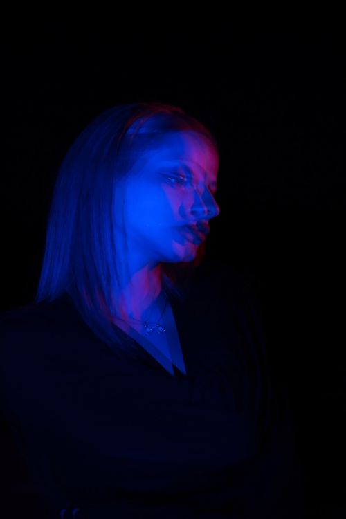 Free Artistic portrait of a woman with dynamic blue and red lighting on a black background. Stock Photo