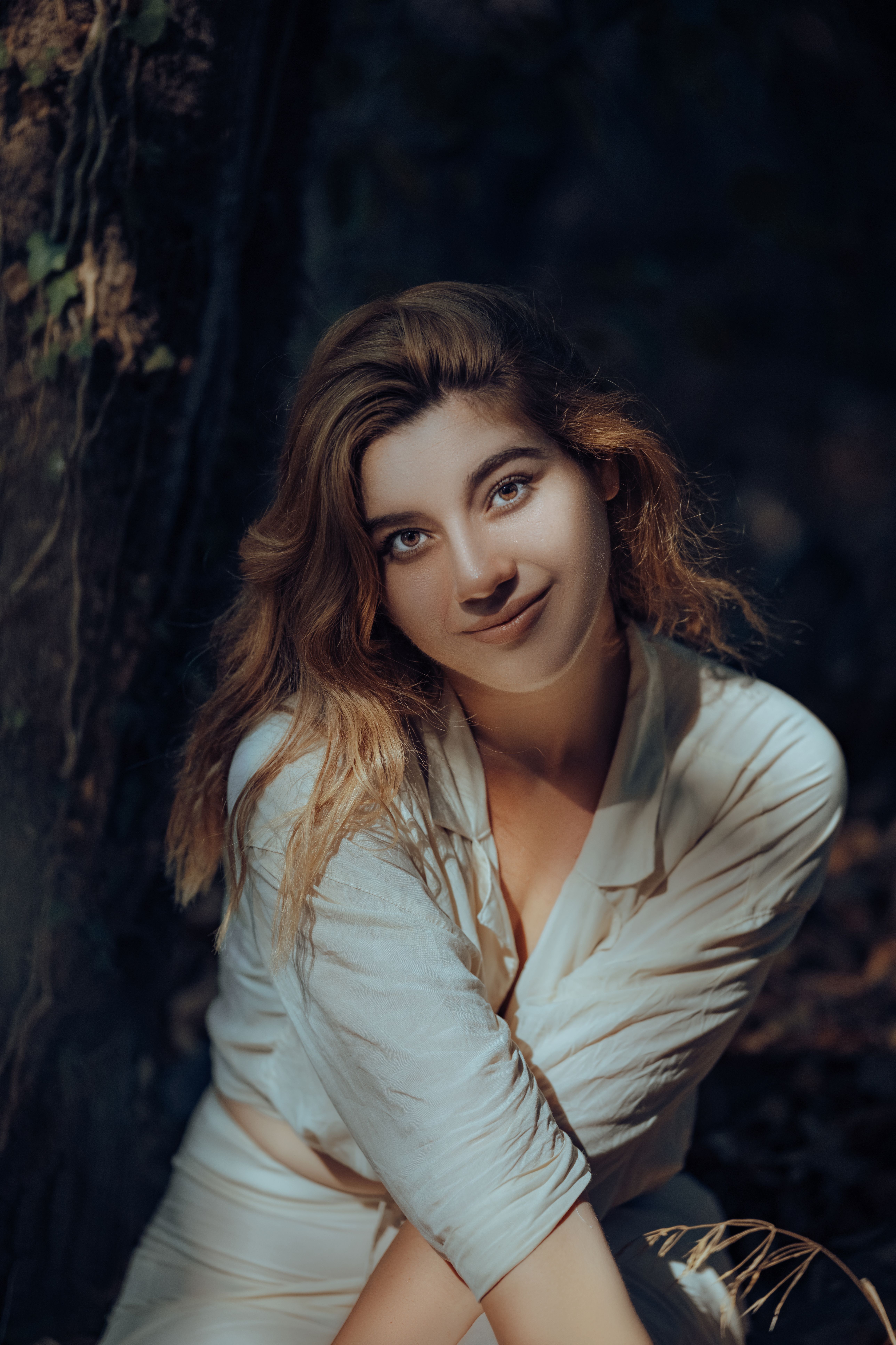 Portrait of a woman in sunlight, surrounded by forest foliage, capturing a serene nature vibe.