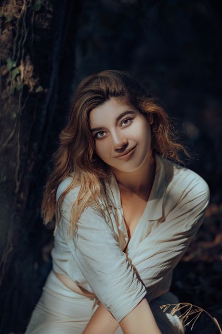 Portrait of a woman in sunlight, surrounded by forest foliage, capturing a serene nature vibe.
