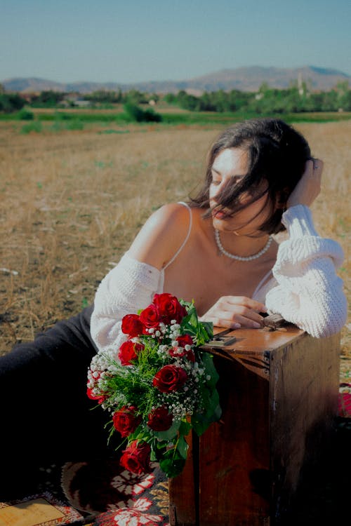 Model Posing in Field with Suitcase and Bouquet