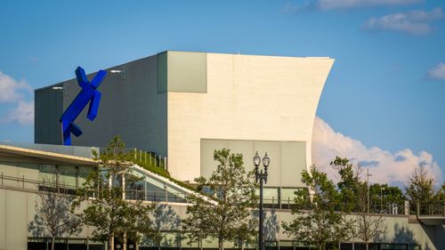 Free A modern architectural building with a striking blue sculpture set against a clear sky. Stock Photo