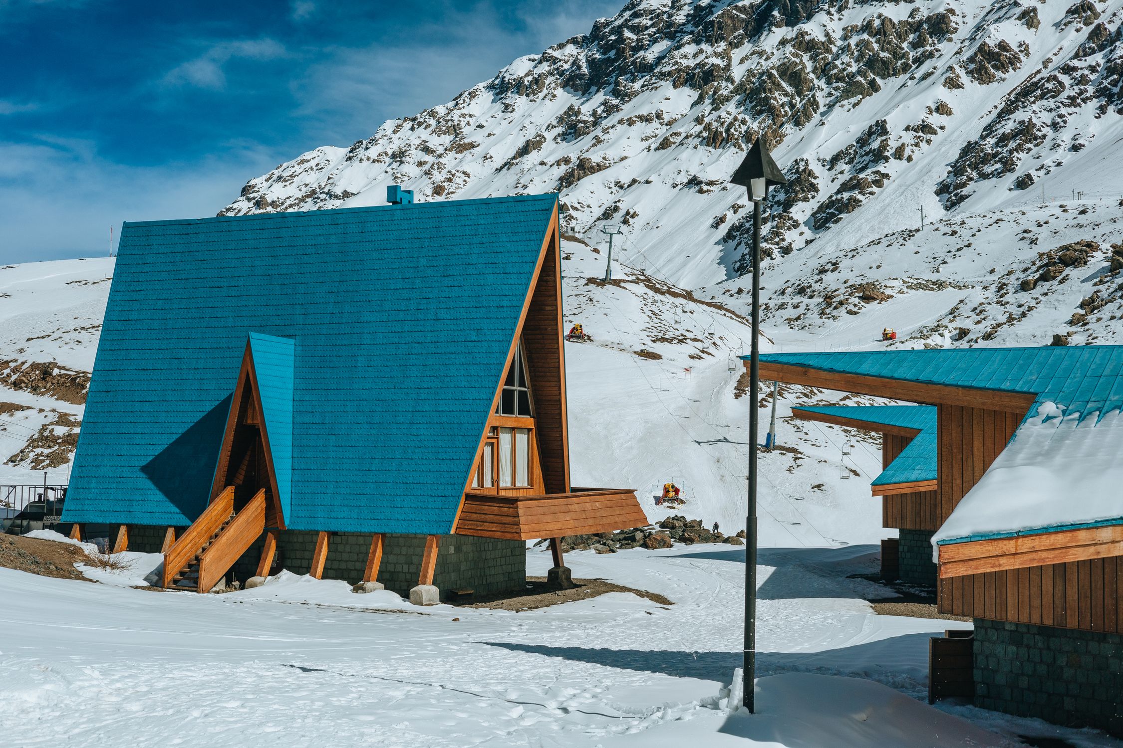 Cozy A-frame cabins nestled in a picturesque snow-covered mountainous landscape, perfect for a winter retreat.