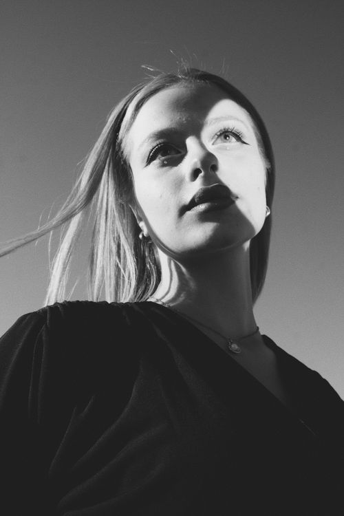 Free Stunning black and white portrait of a woman with sunlight casting dramatic shadows. Stock Photo