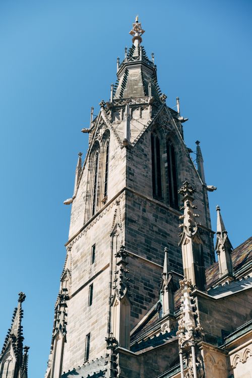 Free A stunning view of a Gothic church tower, showcasing intricate medieval architecture against a clear blue sky. Stock Photo