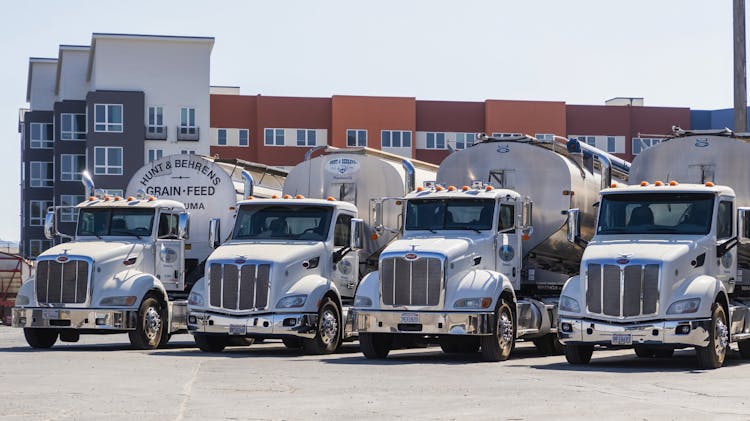 Shiny Peterbilt Trucks With Grain Reservoir Semitrailers Parked At A Factory Yard