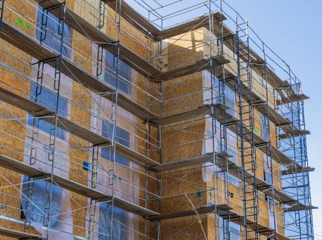 A high-rise building with scaffolding for construction and repair work under a clear sky.