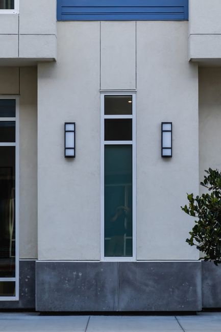Close-up view of a modern building facade featuring vertical windows and wall sconces.