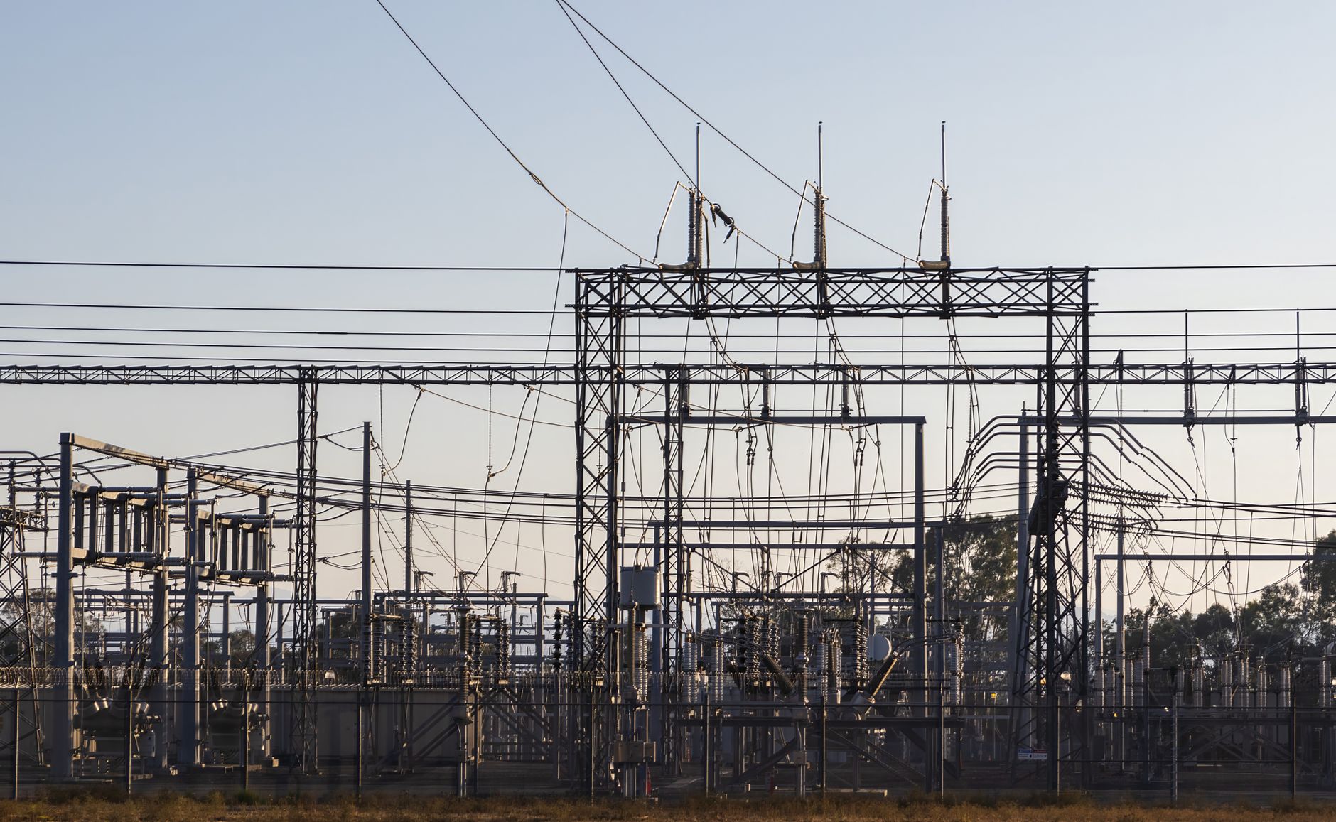 High-voltage electrical substation and transmission lines, illustrating the grid infrastructure AI data-centre clusters need