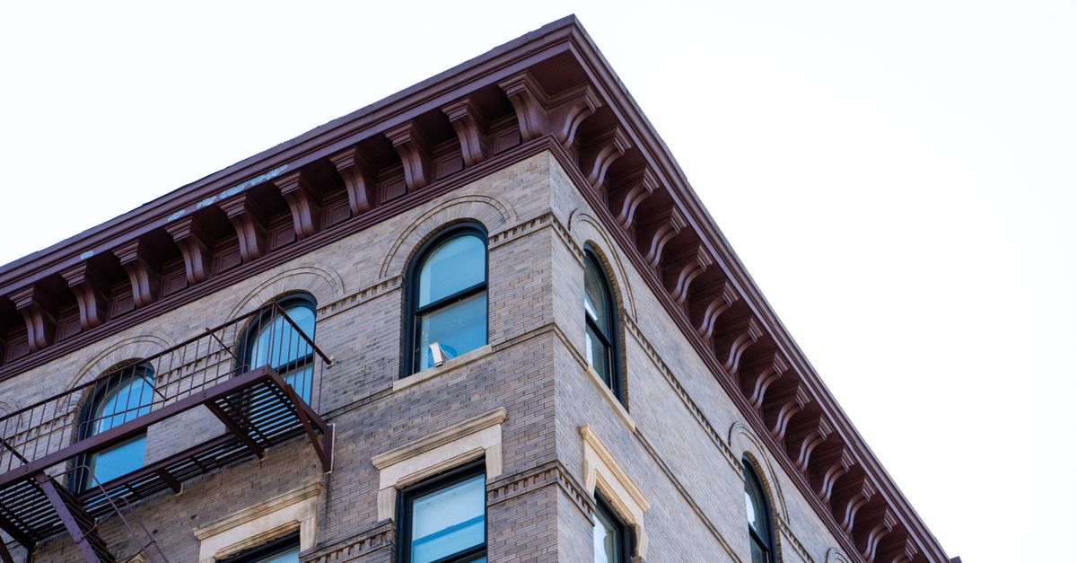 Close-up view of an elegant urban building facade featuring arches, windows, and a fire escape.