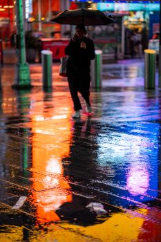 A vibrant urban street at night with reflections and neon lights, depicting a rainy city atmosphere.