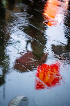A vivid capture of neon sign reflections on a wet city sidewalk during rain.