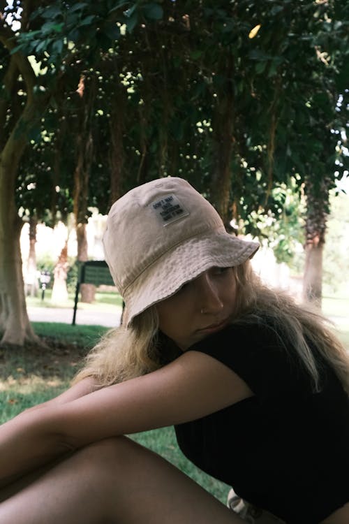 Young Woman in a Bucket Hat Sitting in a Park