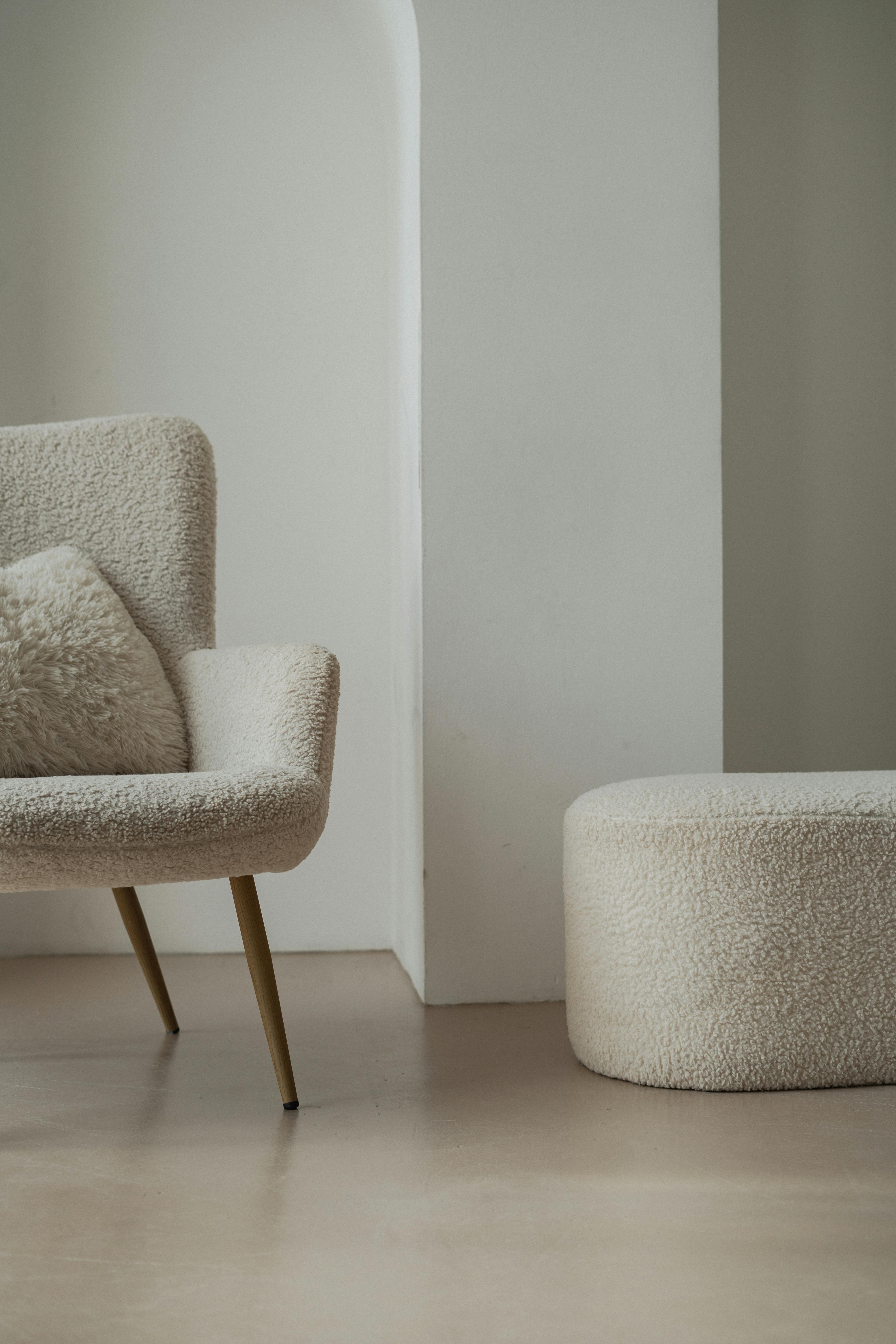 Elegant interior design featuring a white sherpa armchair and footstool, perfect for a cozy modern look.