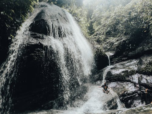 Man Sitting on Rock Near Waterfall