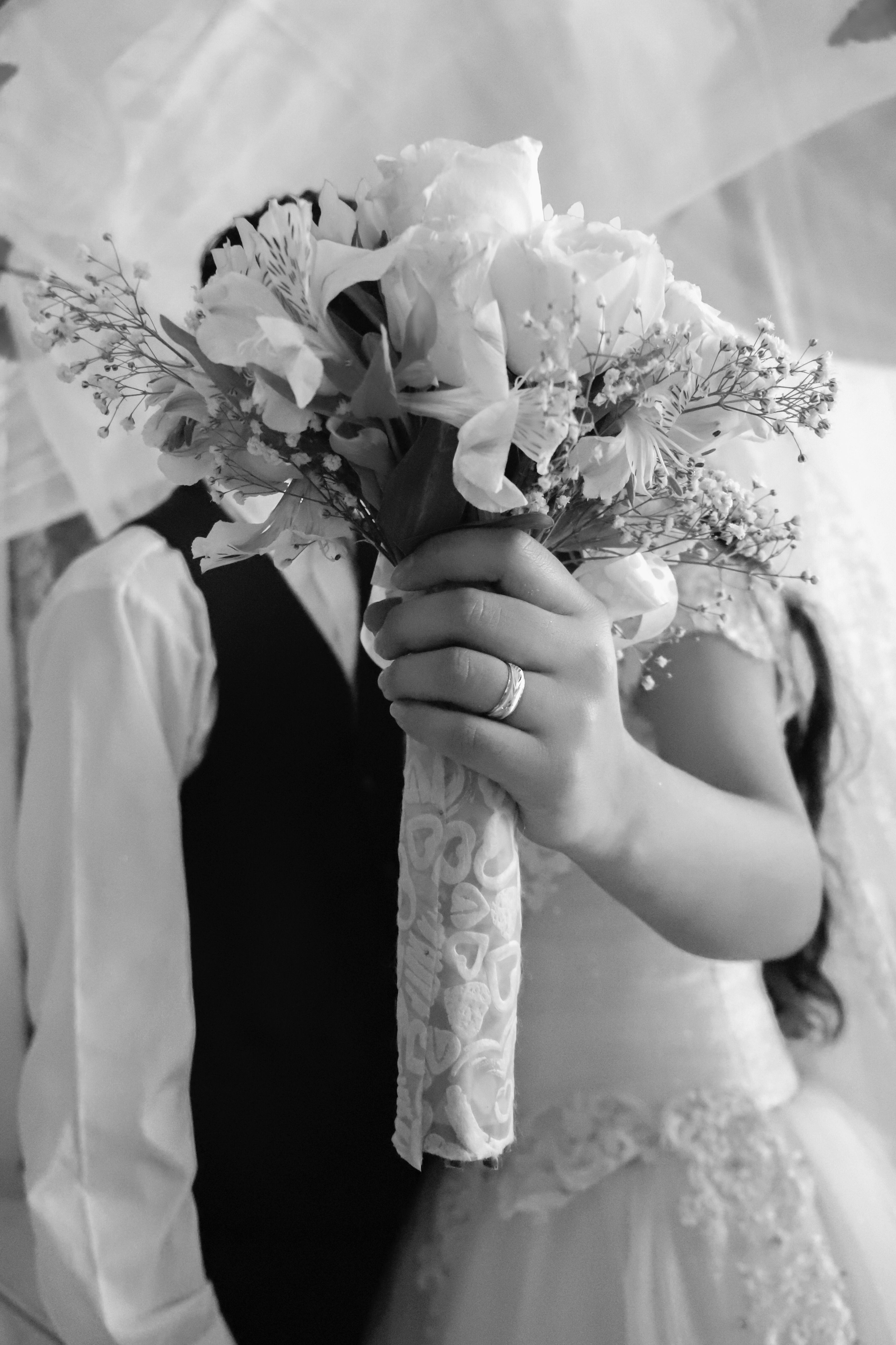 Close-up of a bride holding a bouquet in a black and white wedding scene.